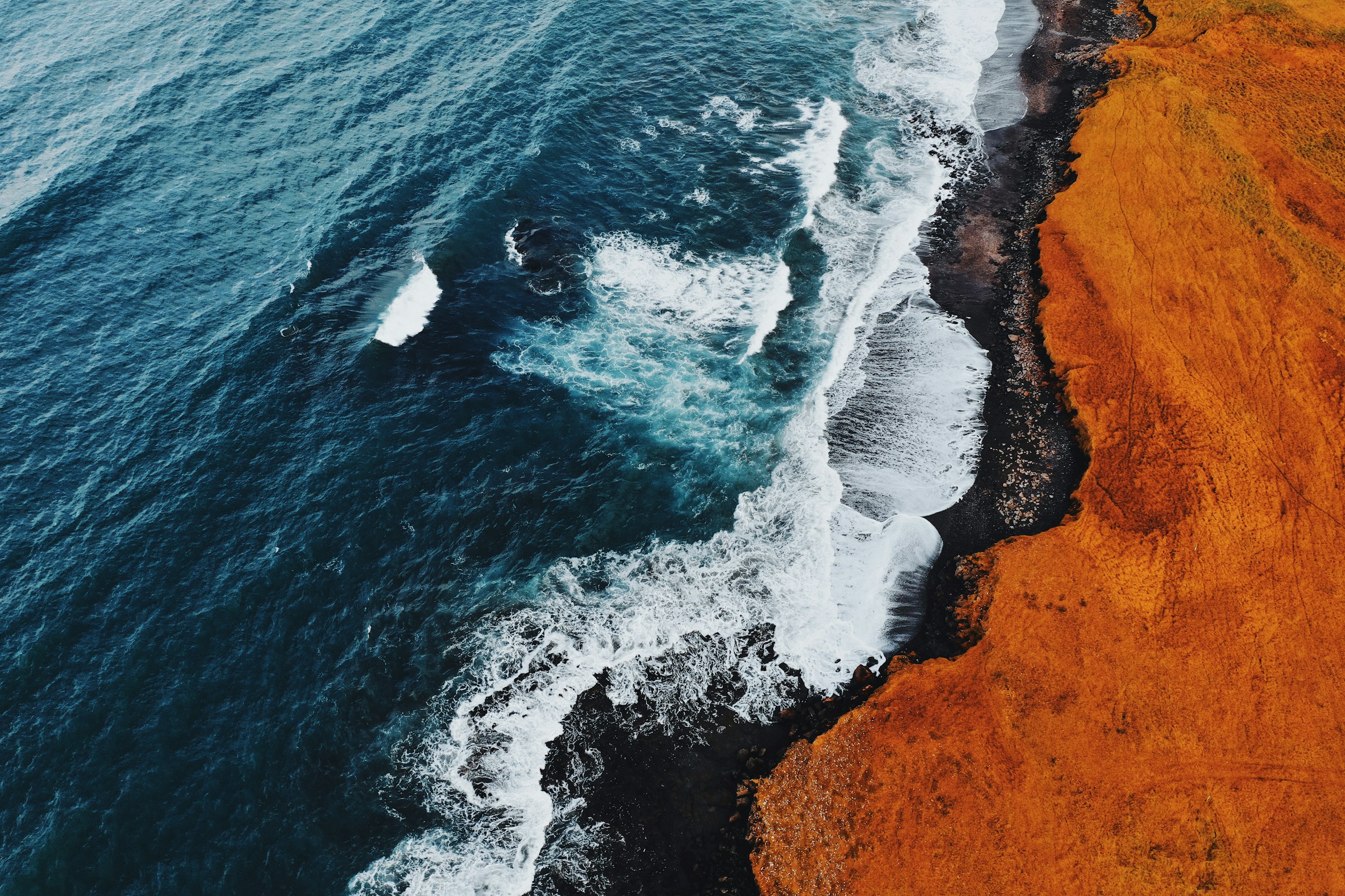 Aerial view of a coastline meeting deep teal water